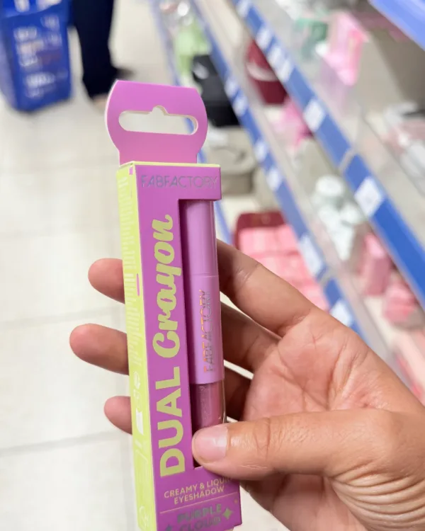 A hand holding the crayon in its box, in a shop aisle, taken on a phone.