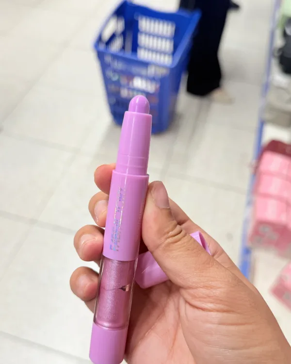 The crayon out of its box, held in a hand in the shop, taken on a phone.