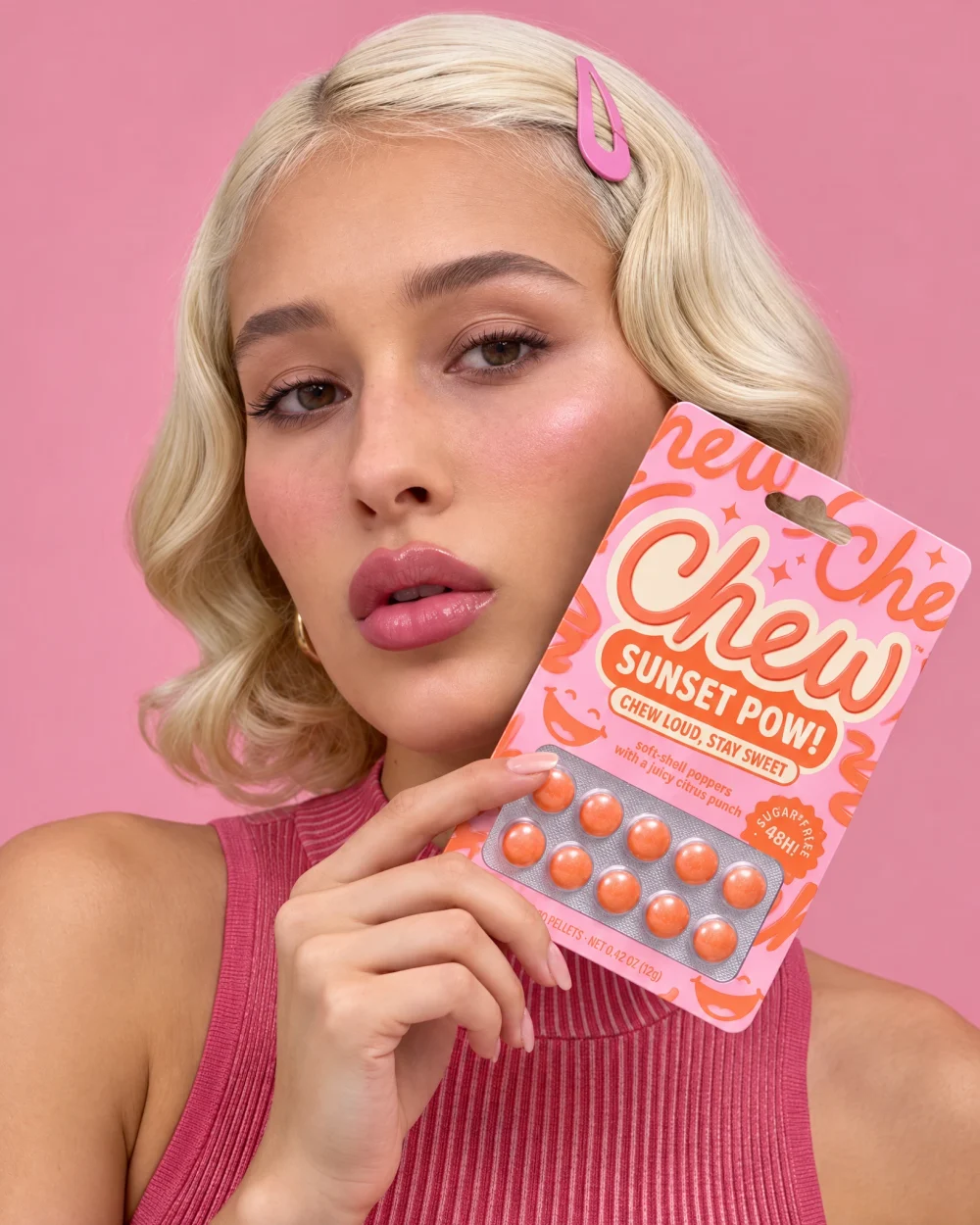 A finished image from the shoot, in high definition: a model holding the same packet against her cheek, on pink.