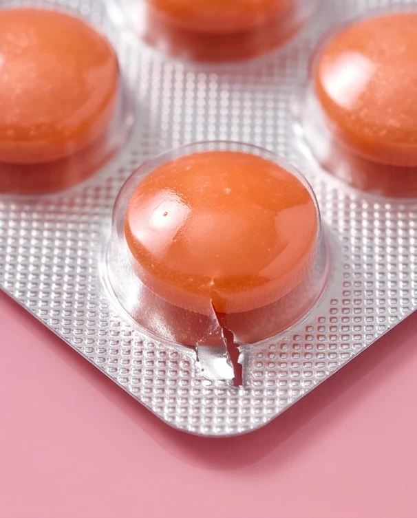 A close-up of the gum in its blister, on pink.